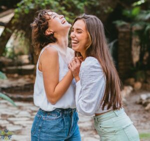 women clasping hands and laughing in a outdoor setting