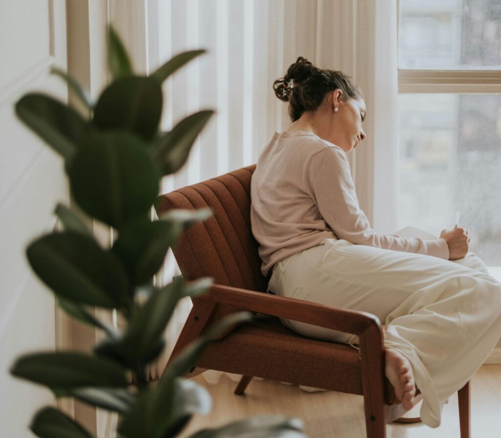 plant in foreground, woman seated reflectively