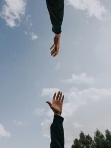 hands reaching toward each other, sky background